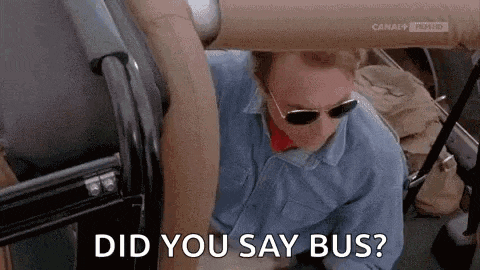 a man wearing sunglasses and a blue shirt is sitting in a bus and asking did you say bus .