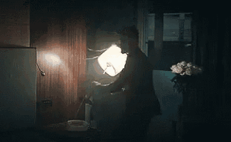 a man is standing in a dark room holding a lantern .