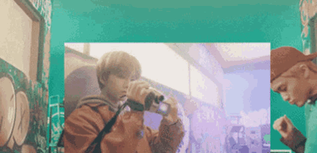 a man is taking a picture with a camera while another man watches .