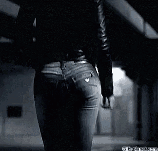 a woman in jeans and a black jacket is walking down the street .