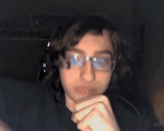 a young man wearing glasses and a headset looks at the camera