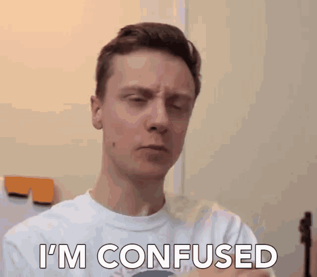 a man in a white shirt says i 'm confused in front of a wall