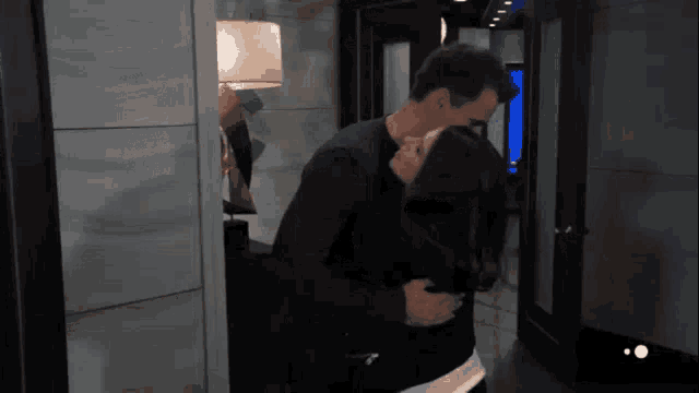 a man is hugging a woman in a hallway in a room .