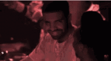 a man with a beard is smiling in a dark room with red lights .