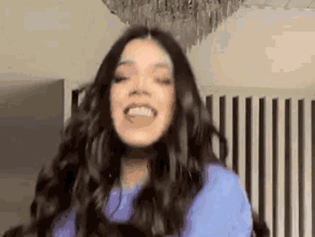 a woman with long dark hair is wearing a purple shirt and smiling .