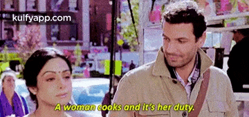 a man and a woman are standing next to each other and the woman is saying a woman cooks and it 's her duty