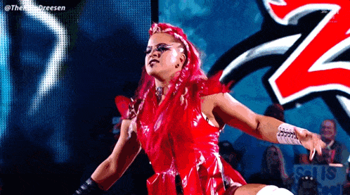 a woman with red hair and a red dress is standing in front of a crowd .