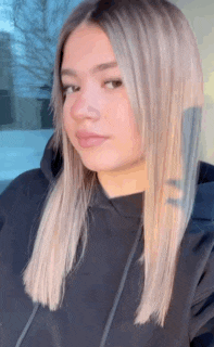 a woman in a black hoodie is looking at the camera .