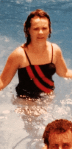 a woman in a black and red striped bathing suit stands in a pool