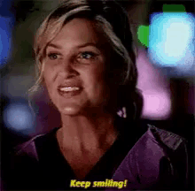 a woman in a purple scrub top is smiling and says keep smiling .