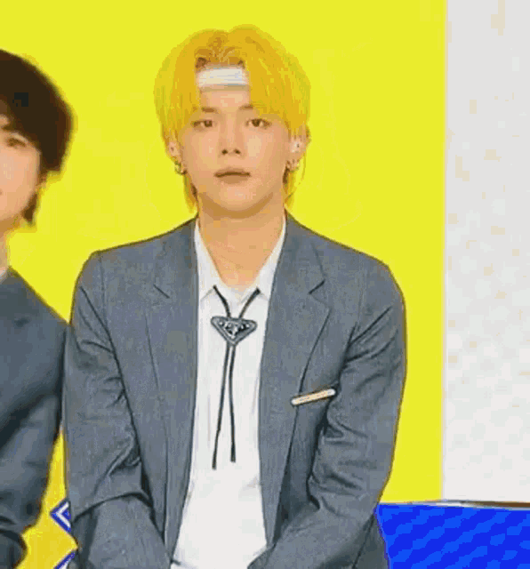 a man in a suit and tie is sitting in front of a yellow background .