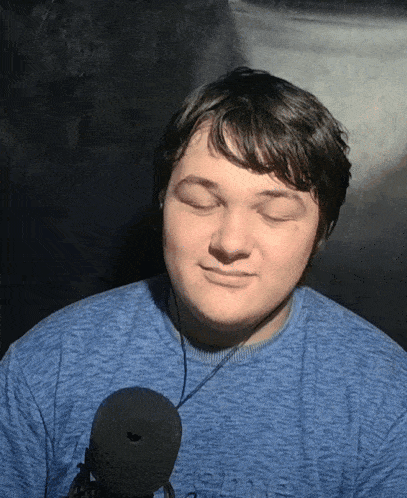 a young man wearing a blue shirt and headphones is smiling