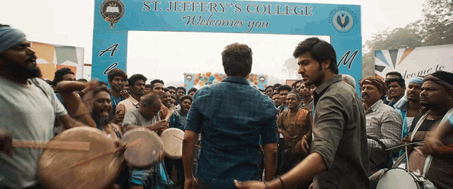 two men are standing in front of a sign that says st. jeffery 's college welcomes you