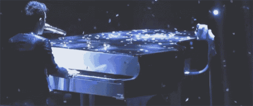 a man is playing a piano in front of a blue background