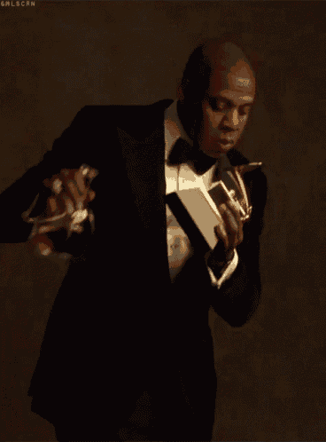 a man in a tuxedo is holding a book and a bottle