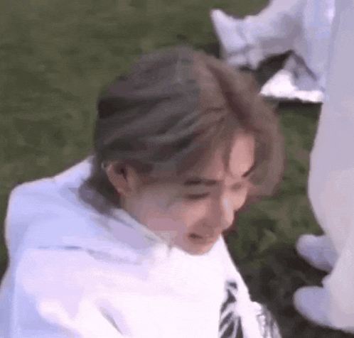 a close up of a person 's face while sitting on the grass .
