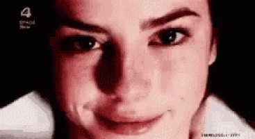 a close up of a woman 's face with a red background and a smile on her face .