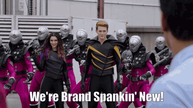 a man is standing in front of a group of robots and says we 're brand spankin new