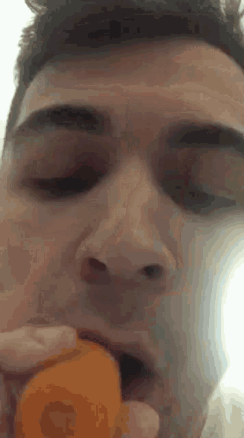 a man is eating an orange with his eyes closed .