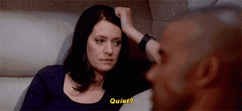 a woman is sitting next to a man on a couch and holding her hand to her head .