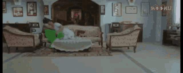 a couple is sitting on a couch in a living room with a green pillow .