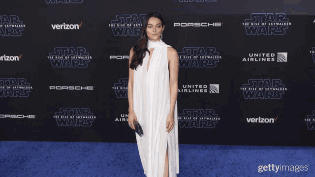 a woman in a white dress is standing in front of a blue star wars backdrop