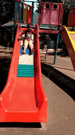 a little boy is playing on a slide in a playground