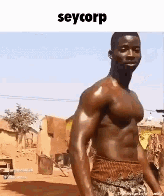 a shirtless man is standing in a dirt field in front of a building .