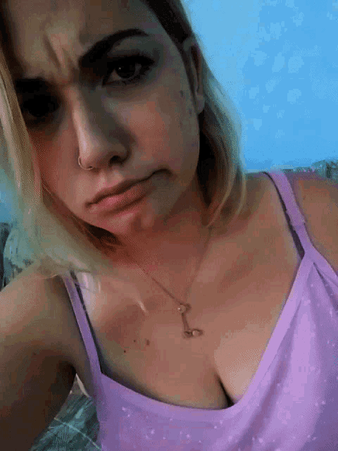 a woman in a purple tank top has a necklace with a letter l on it