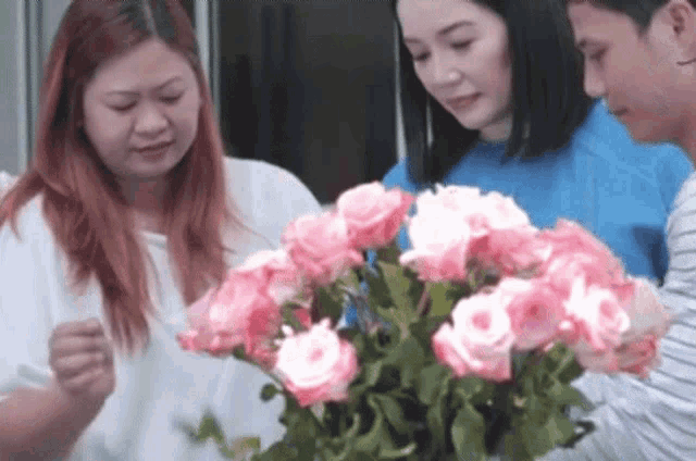 a group of people looking at a bouquet of pink roses