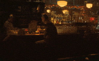 a man sits at a bar drinking from a bottle
