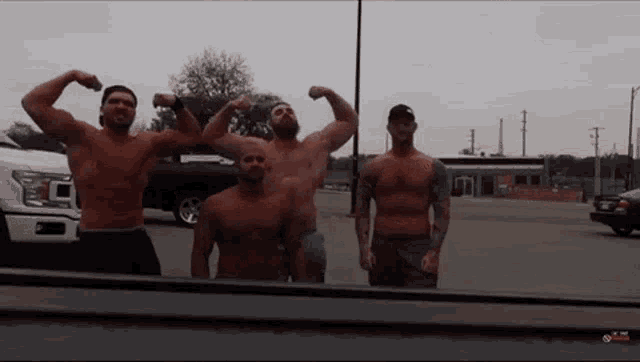 a group of men flexing their muscles in front of a truck