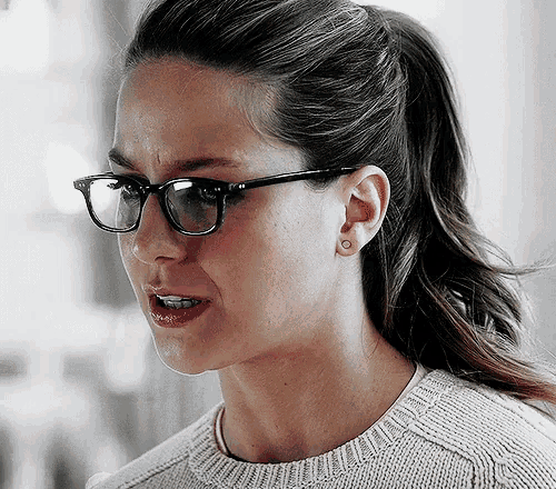 a close up of a woman wearing glasses and a ponytail