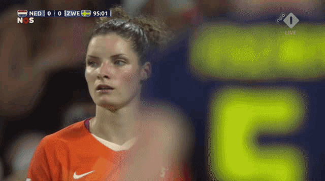 a female soccer player stands in front of a scoreboard that says 5 on it