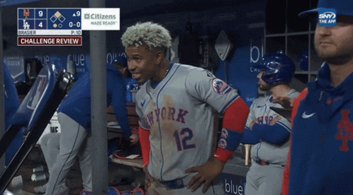 a new york mets player stands in a dugout