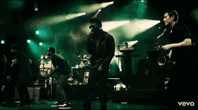 a man singing into a microphone while playing a saxophone on a stage with the word vevo in the corner
