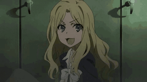 a blonde anime girl with long hair and blue eyes is smiling while standing in a dark room .