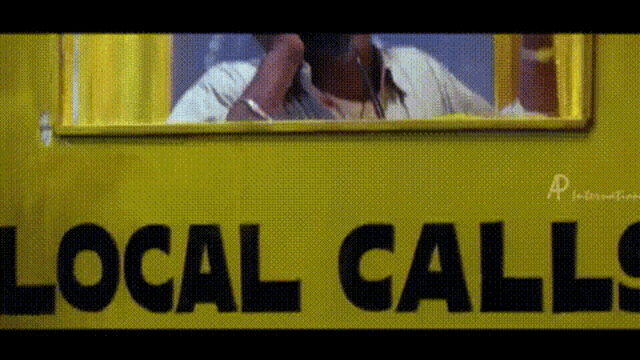 a man is talking on a phone in front of a yellow sign that says local calls