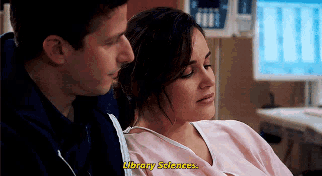 a woman in a hospital gown is talking to a man in front of a computer monitor .