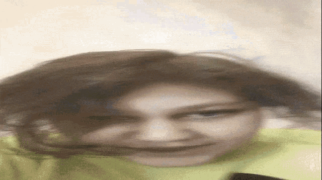 a blurry picture of a woman making a funny face with her hair blowing in the wind