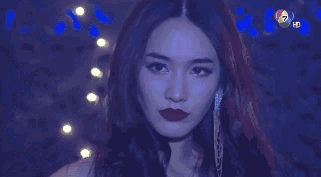 a woman with red lipstick looks at the camera with the number 7 on the bottom right corner