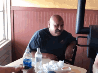a man sits at a table with a bottle of aquafina water in front of him