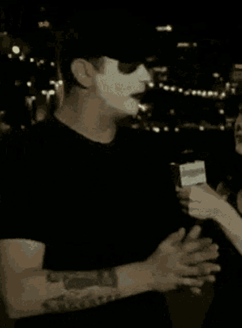 a man wearing a mask and sunglasses is being interviewed