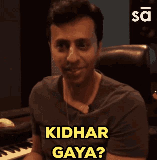 a man is sitting in front of a keyboard and says " kidhar gaya "