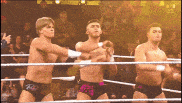 three wrestlers are in a ring and one has the letter b on his underwear