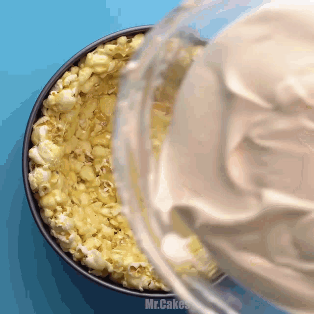 a bowl of popcorn with whipped cream being poured over it