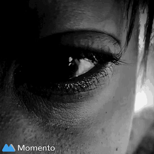 a woman 's eye is shown in a black and white photo with a momento logo
