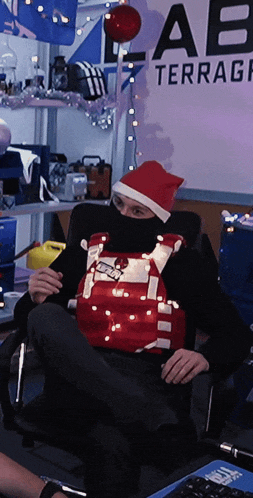 a man wearing a santa hat is sitting in front of a wall that says terrace