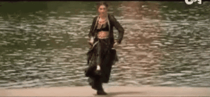 a woman in a crop top is walking across a body of water .