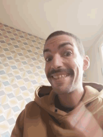a man with a beard is smiling in front of a wall with squares on it